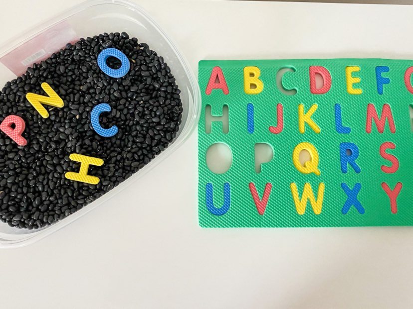 black bean sensory bin with foam letter pieces 