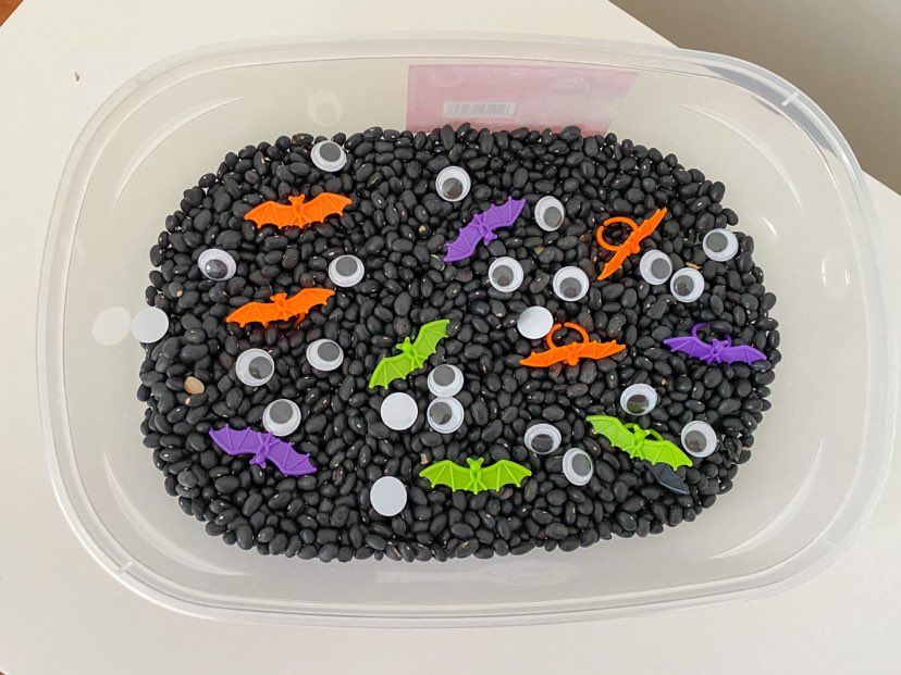 Halloween sensory bin; black beans, google eyes and bat rings