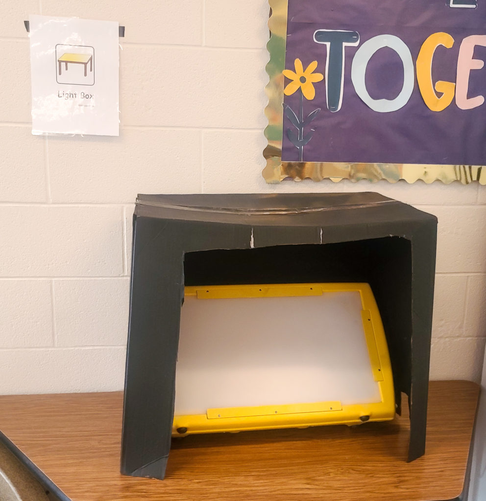 Yellow light box with a painted black box over it.