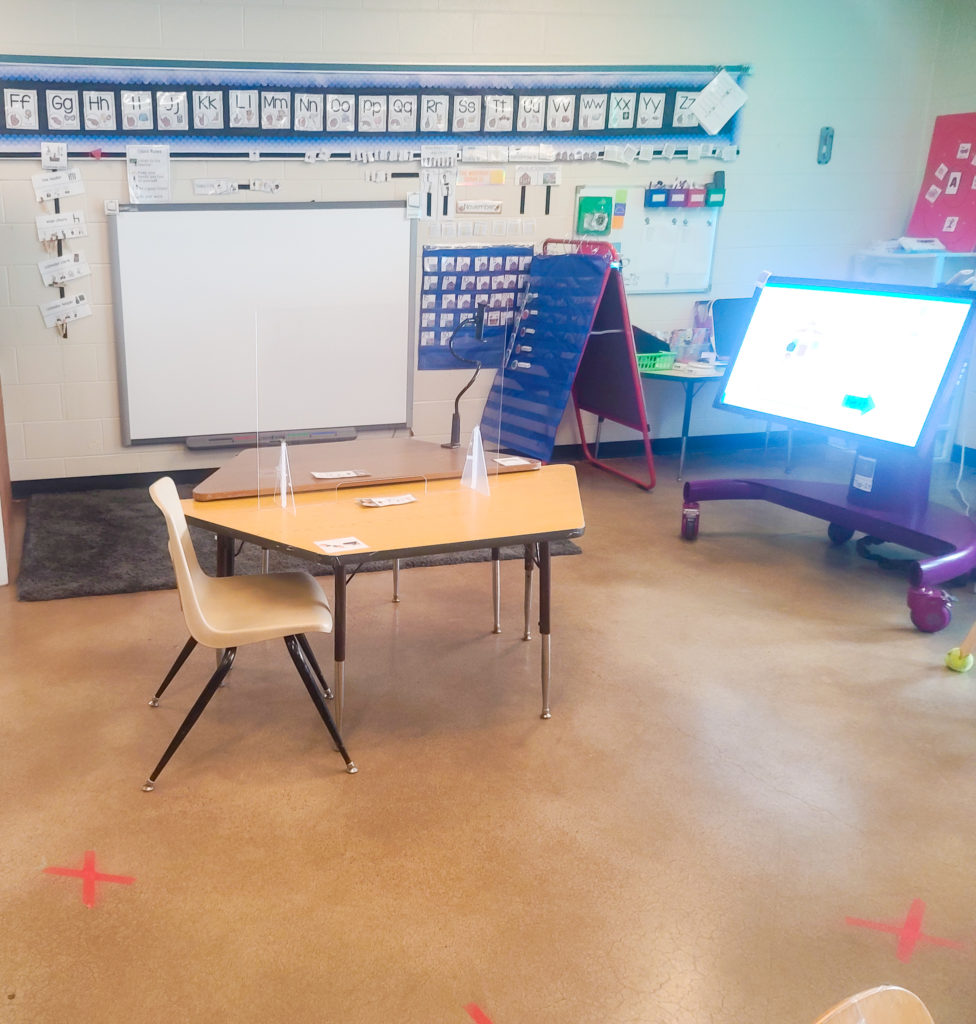 Large area with a gray rug, white board, and blue pocket chart.