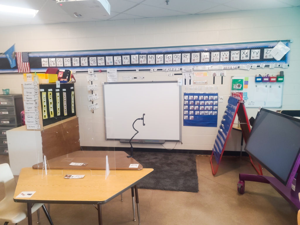 View of student tables, with name tags separated with plexiglass divider.