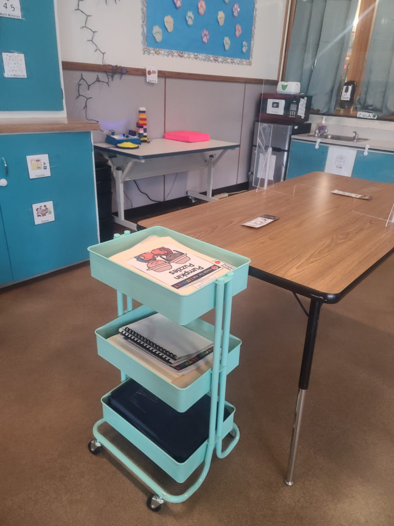 Long table with blue cart holding file folder activities at the end.