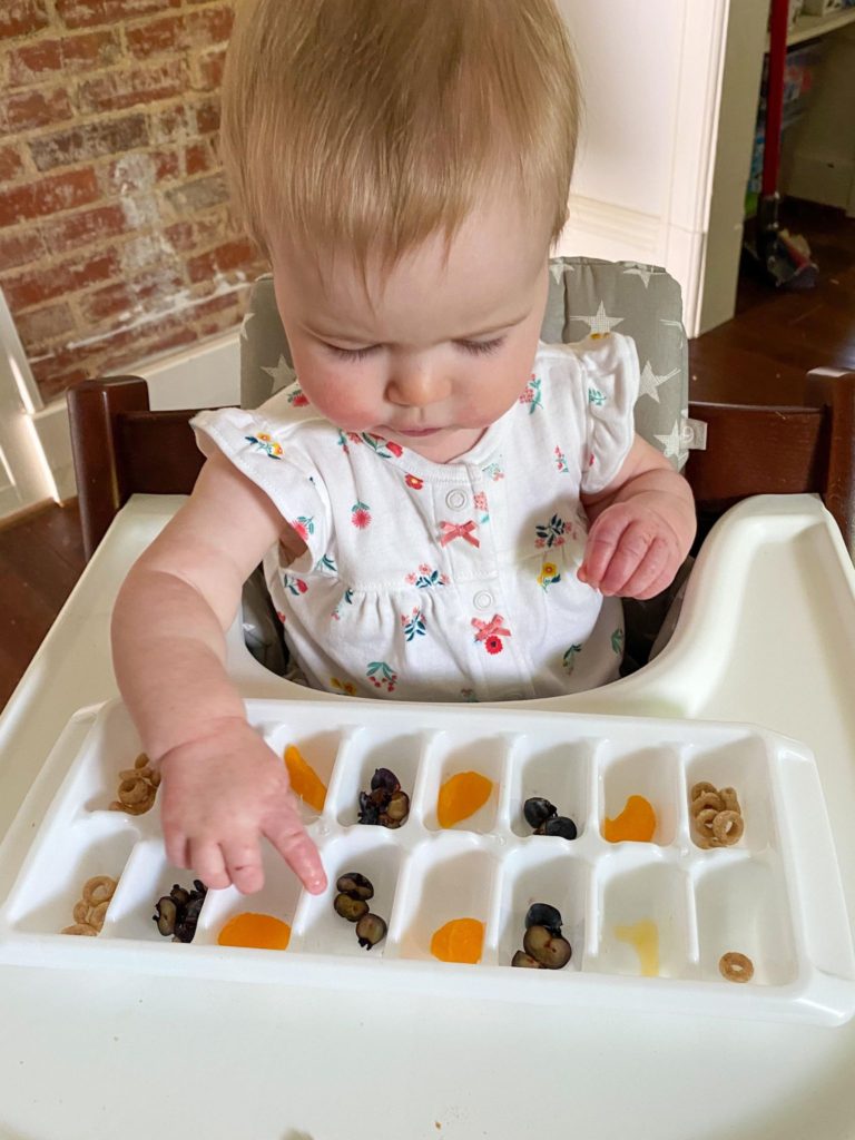 Child eating a snack out of an ice-cube tray