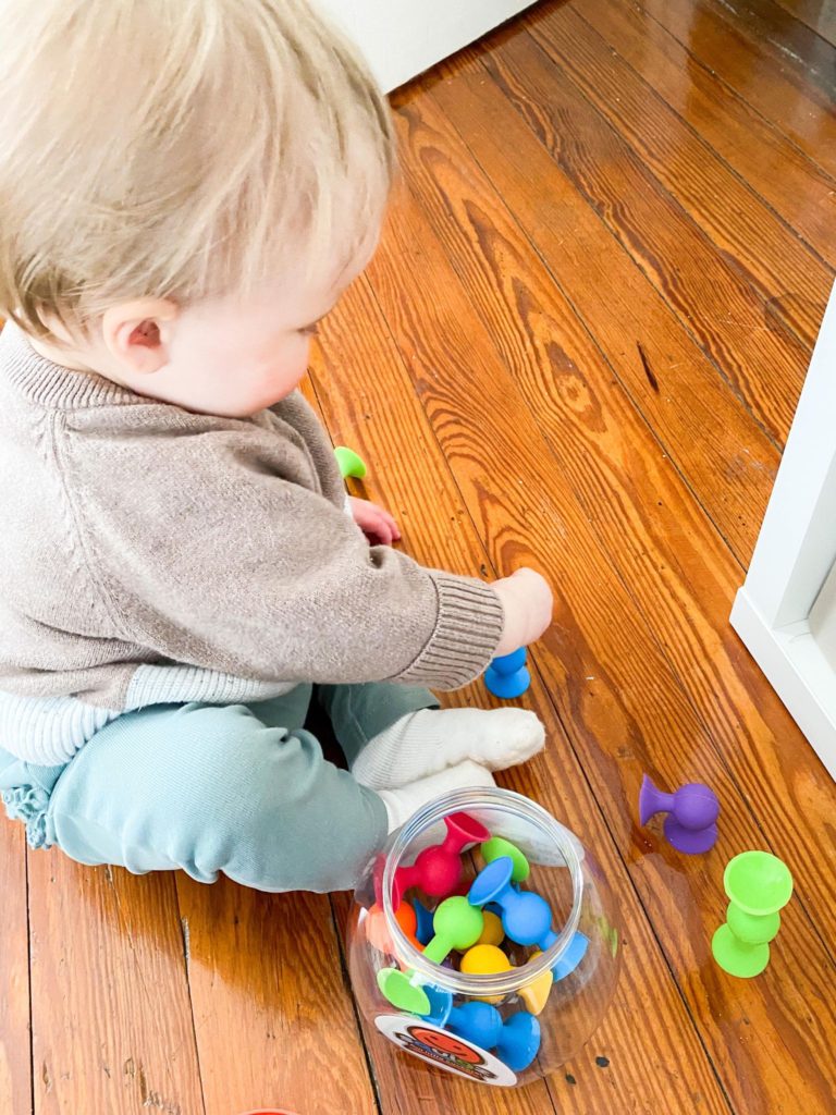 Small child utilizing grasping skills with Squigz toy 