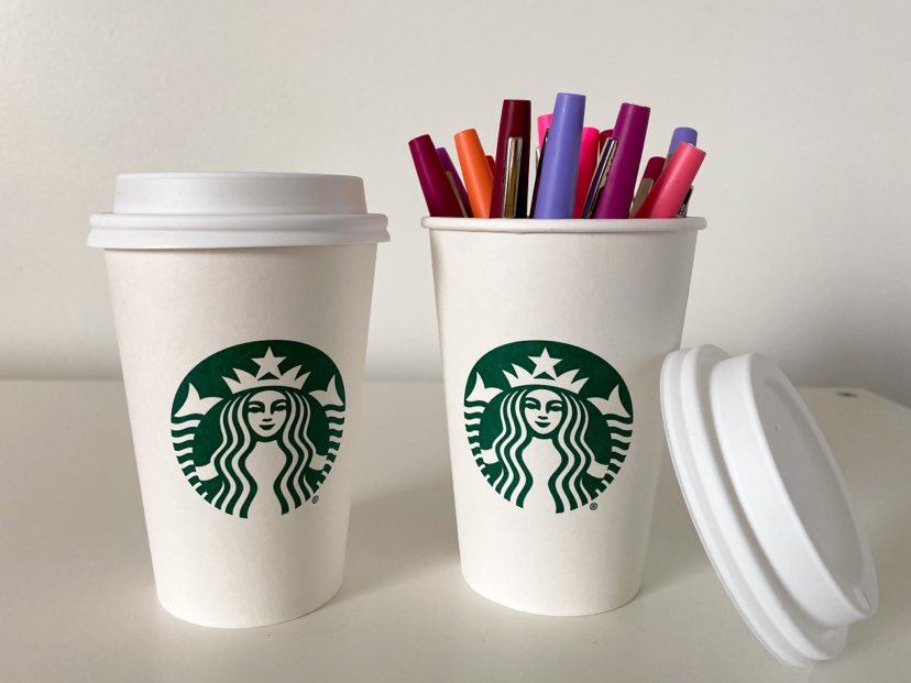 Two small Starbucks cups with pink/purple markers in the cup on the right 