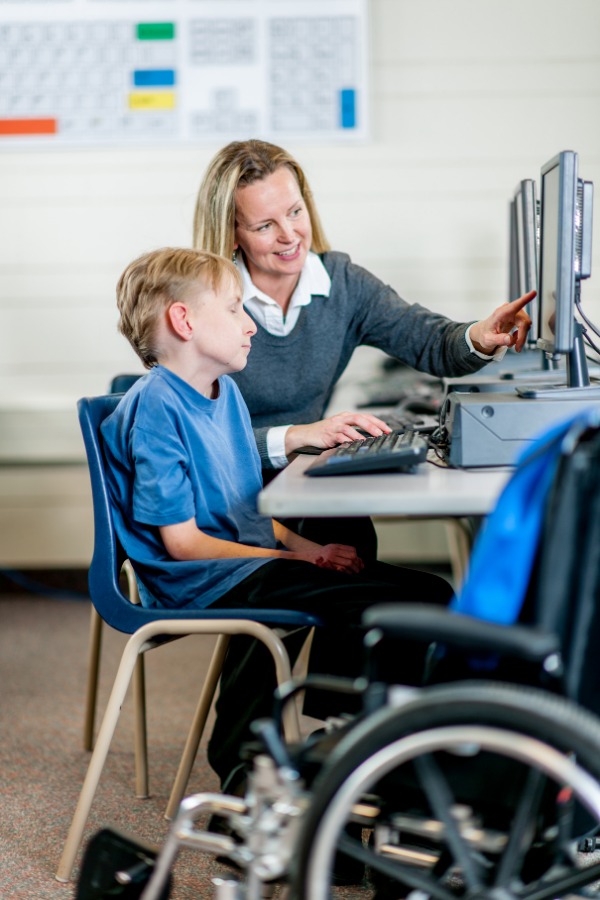 A student and a teacher working on the computer.