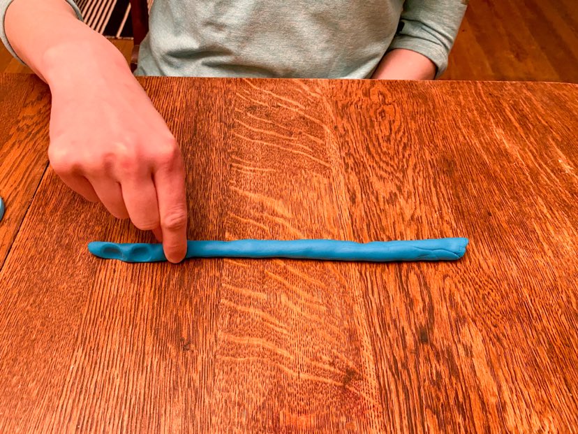a demonstration of pinching playdough. Playdough is rolled out and the author is using index finger/thumb pinching playdough 