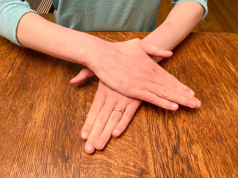 two hands on top of each other pushing playdough down to form a 'pizza' or 'pancake' 