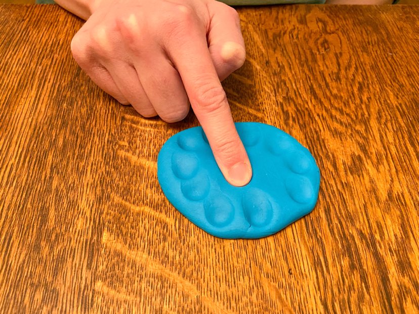 demonstrating using an isolated index finger to press playdough in. 