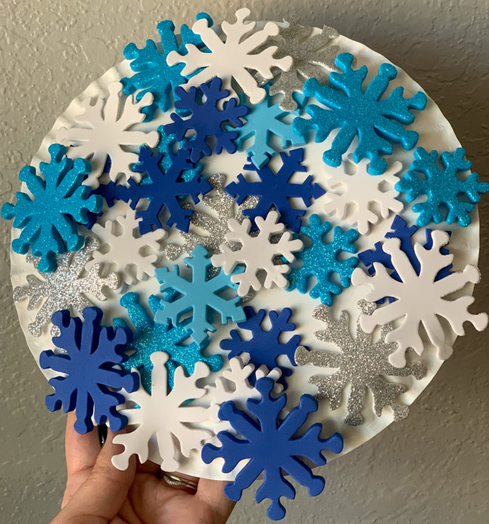 This is a photo of a snowflake mosaic made with a paper plate and sticky foam snowflakes.