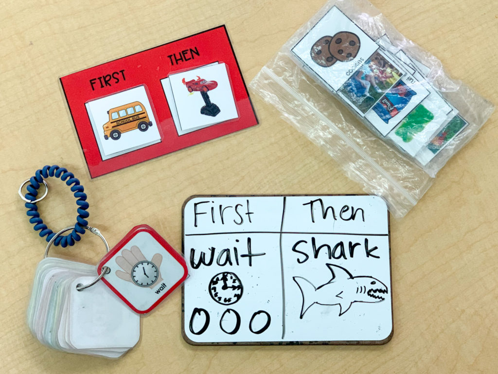 Here is a photo of a visuals key ring that shows a picture for wait, a first/then board, a white board with first wait, then shark, and a bag of visuals.