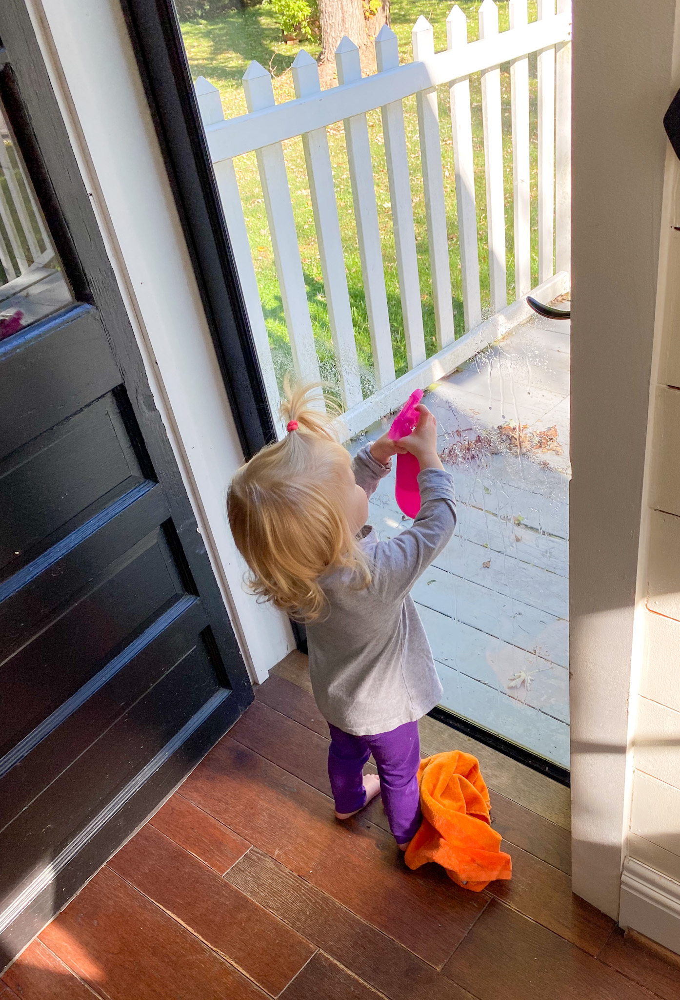 Child spraying windows with a small spray bottle