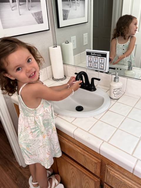 This is a picture of a girl using a communication board to follow steps for using the bathroom. 
