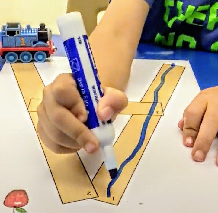 student uses a fat Expo dry erase marker to trace the letter A after he built the letter as a pre-writing strategy