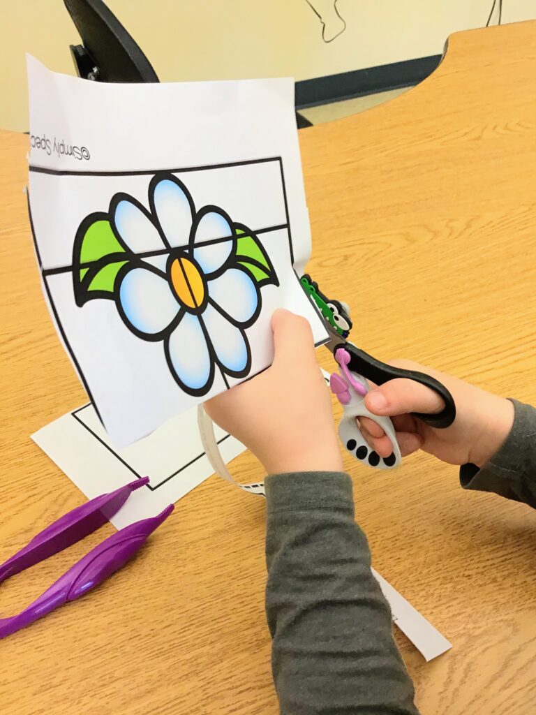 OT student cutting with spring loaded scissors and a Hungry Cutter using the Simply Special Ed cut and paste resource