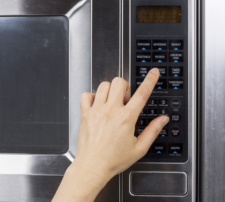 person pressing the buttons on a microwave