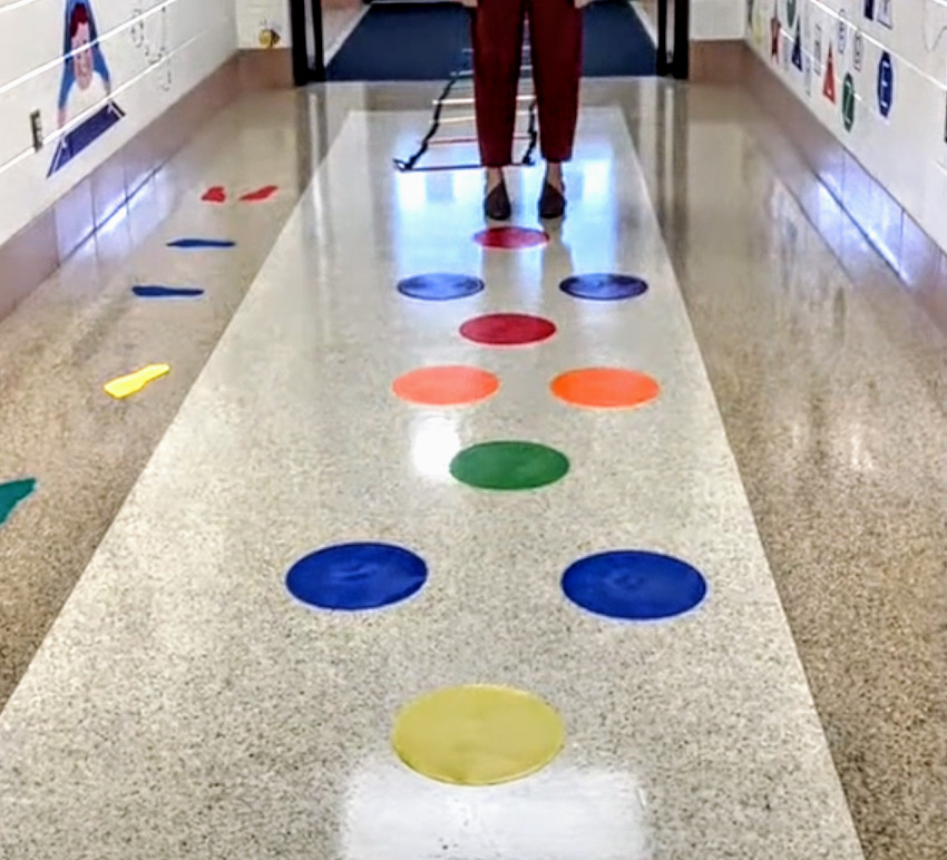 poly spots [circular and feet shaped] on the floor near the sensory wall with someone waiting to jump on the targets