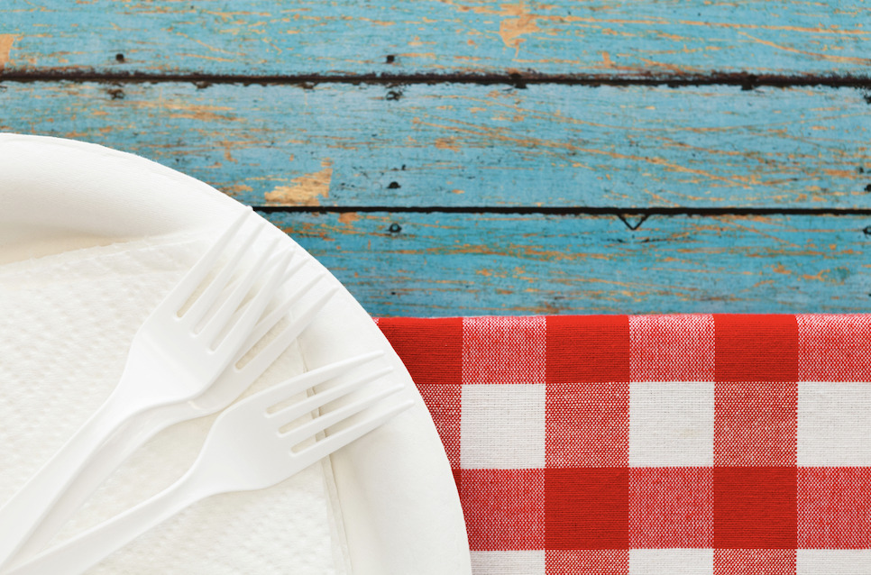 a table cloth, plate, napkin and plastic forks on a table