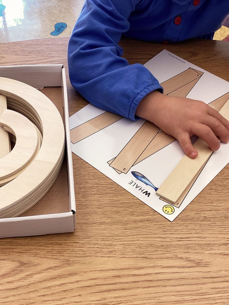 student builds the letter W using Handwriting Without Tears wooden pieces as a multi-sensory approach to letter formation