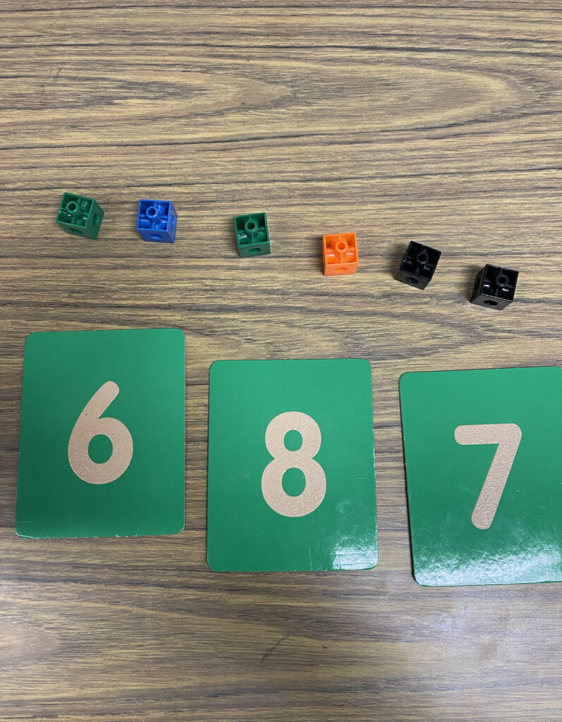 A row of 6 math counting cubes with tactile friendly flashcards below reading the numbers 6, 8 and 7.
