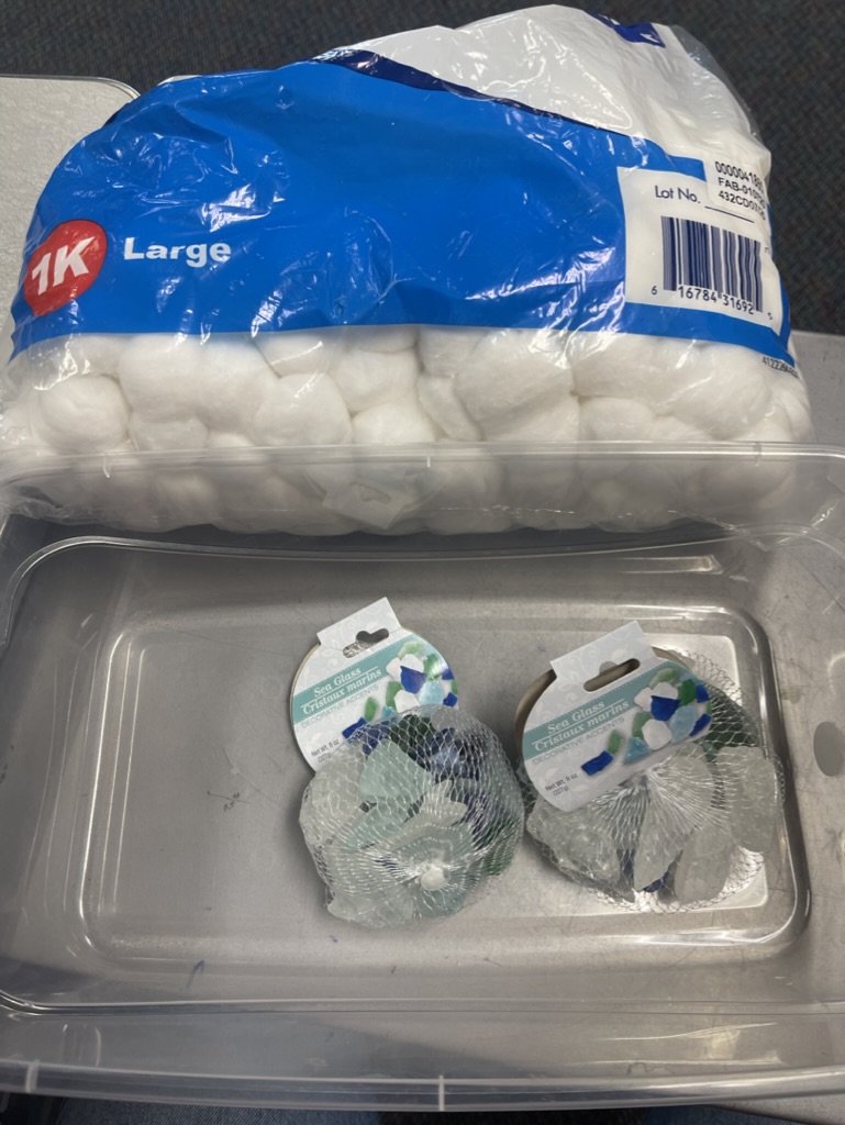 Materials for cloudy sensory bin including a bag of cotton balls and a bag of blue rocks. 
