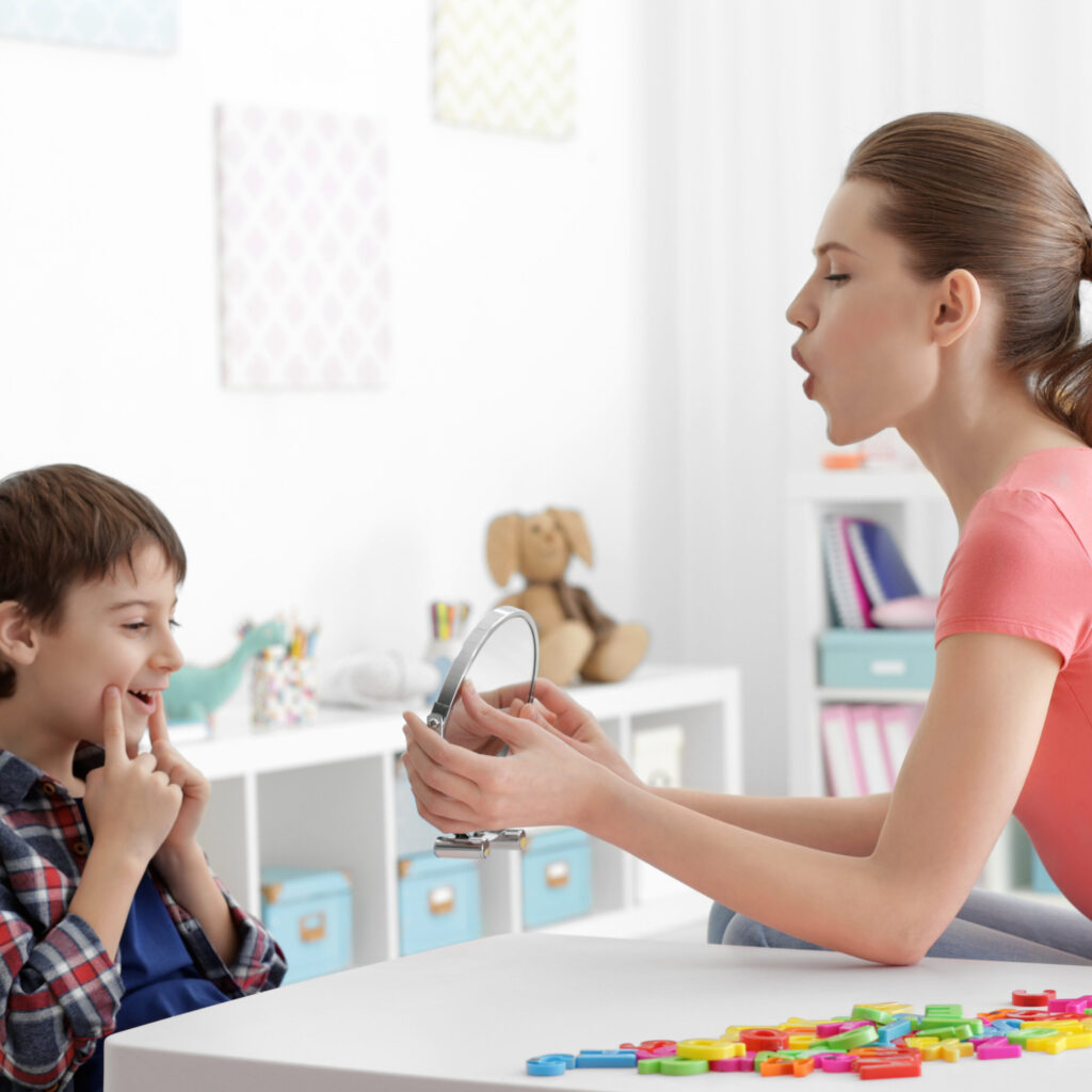 This is an image of an SLP and student using a mirror during articulation therapy.