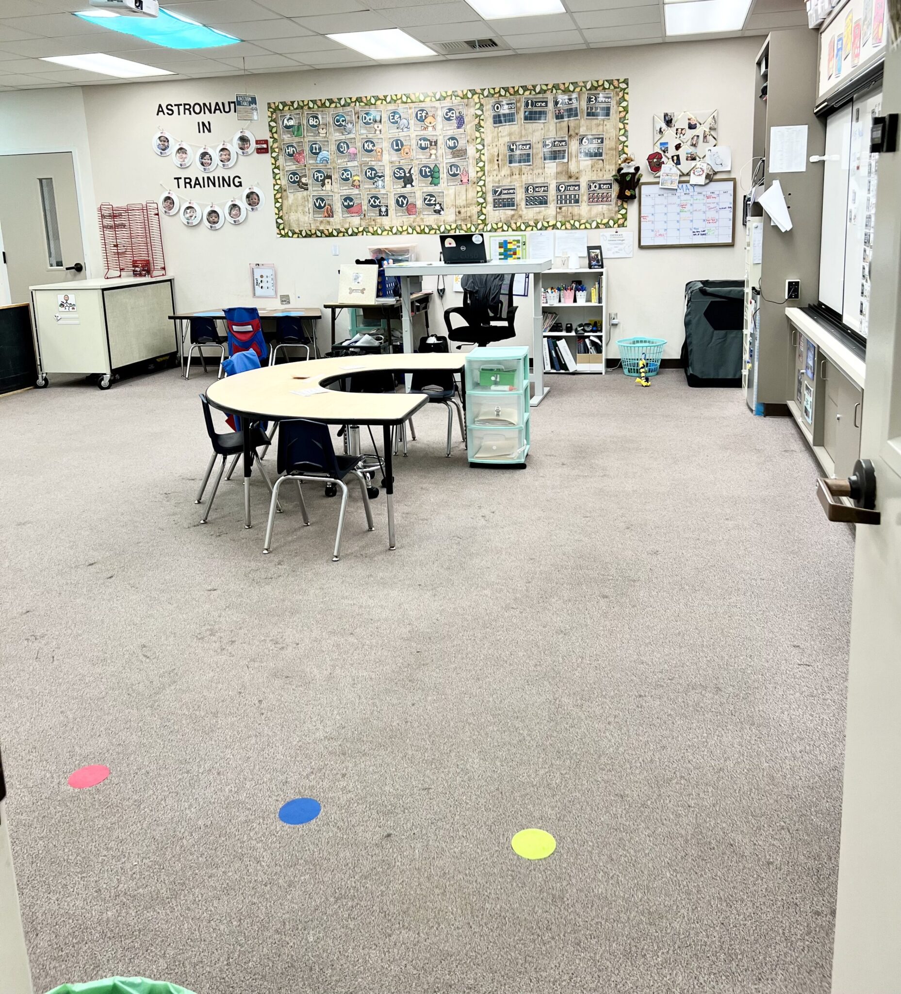 Autism classroom setup with kidney table in center and colored velcro dots on floor for lining up. 