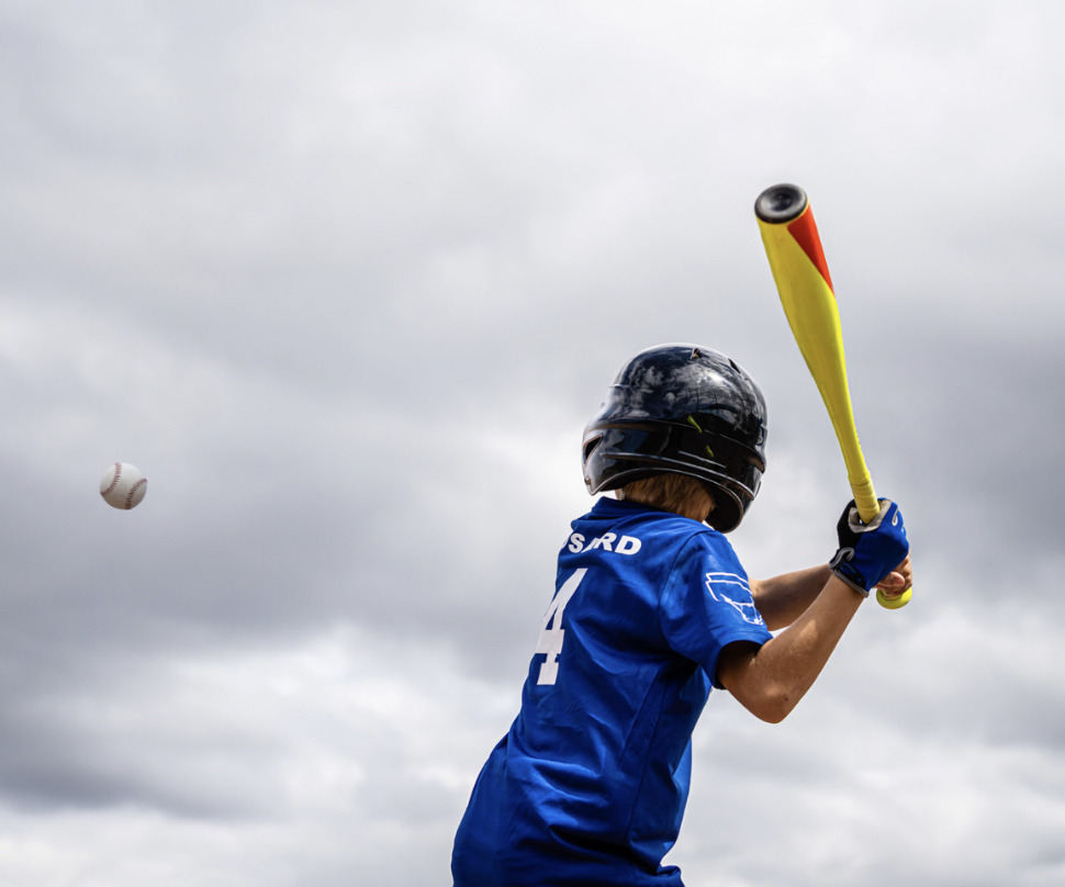 boy wearing a helmet about to swing and hit a baseball with a yellow bat