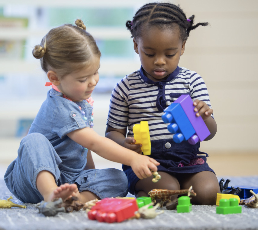 Two preschool girls playing with large Duplo blocks