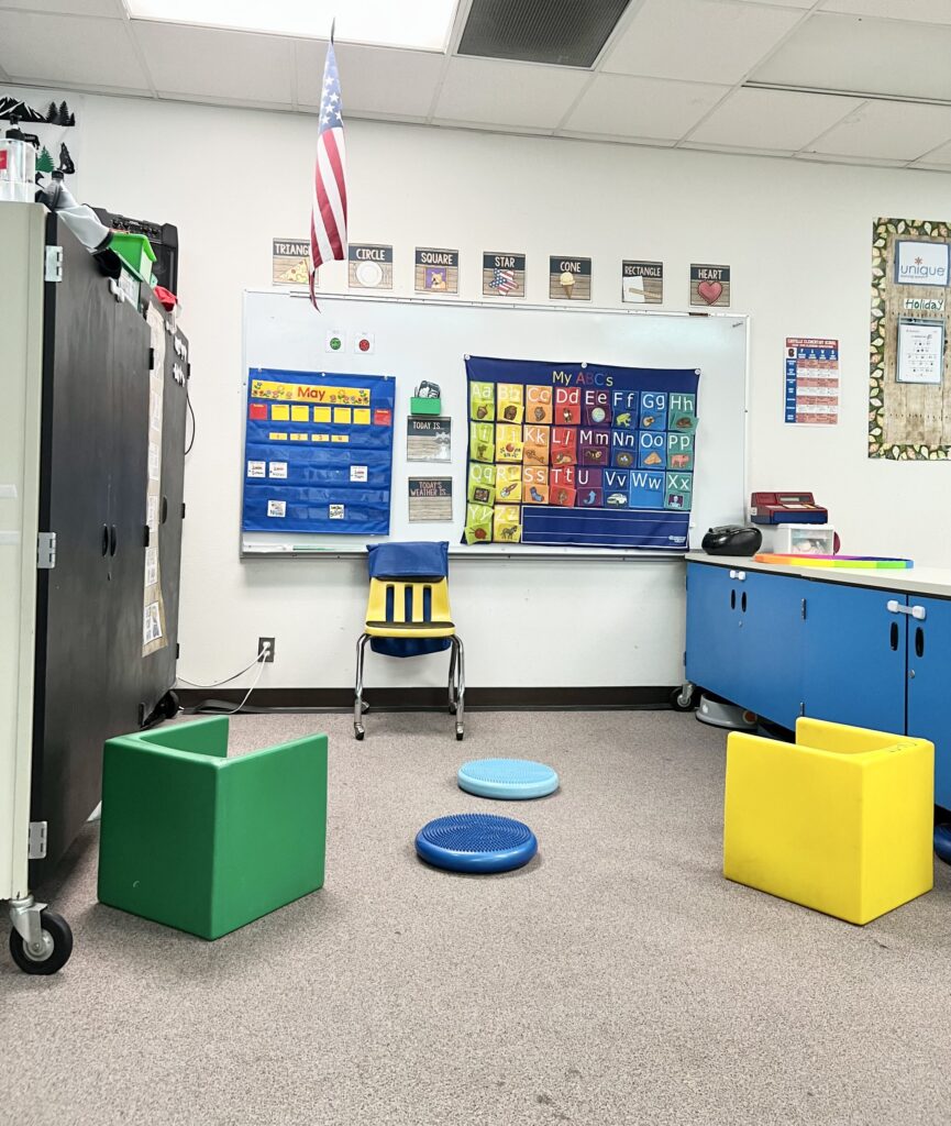 Circle time area for students with autism with cube chairs, wobble cushions, a calendar and ABC chart.