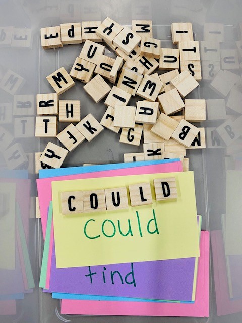 A task box with sight words written on index cards and wooden letter tiles.
