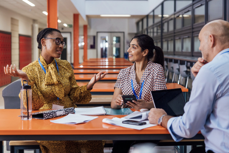 three teachers sitting at a table discussing a student 
