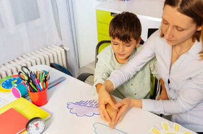 Image of a teacher using hand-over-hand physical prompting to direct a child to point to a picture.