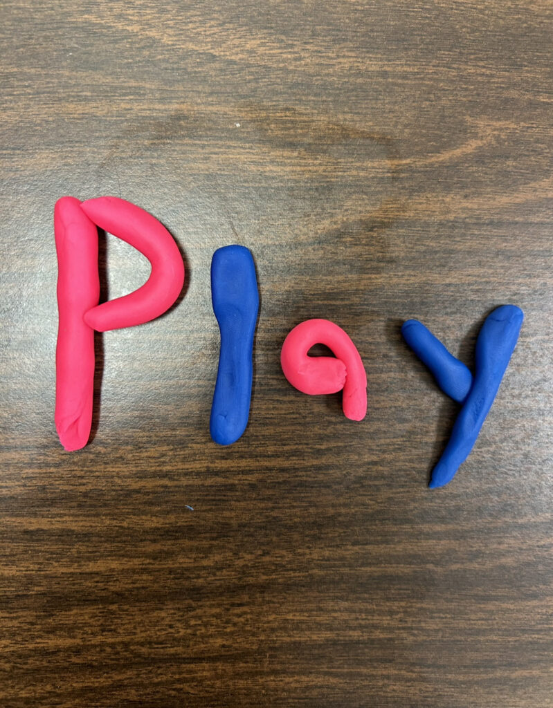 blue and pink play dough rolled into letters spelling "play"
