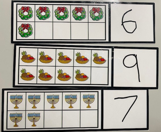 Three ten-frame cards are shown. There is a card with 6 wreaths, a card with 9 bowls of fruit, and a card with 7 menorahs.