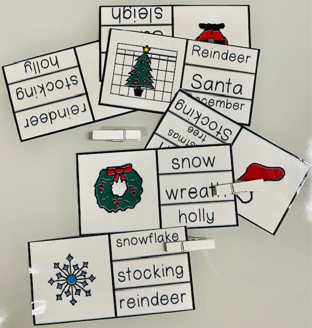 A set of vocabulary clip cards and white clothespins on a white background. The cards have images of a wreath, snowflake, a stocking, and December.