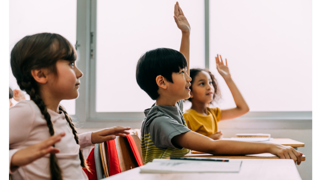 Kids raising hands in the classroom.