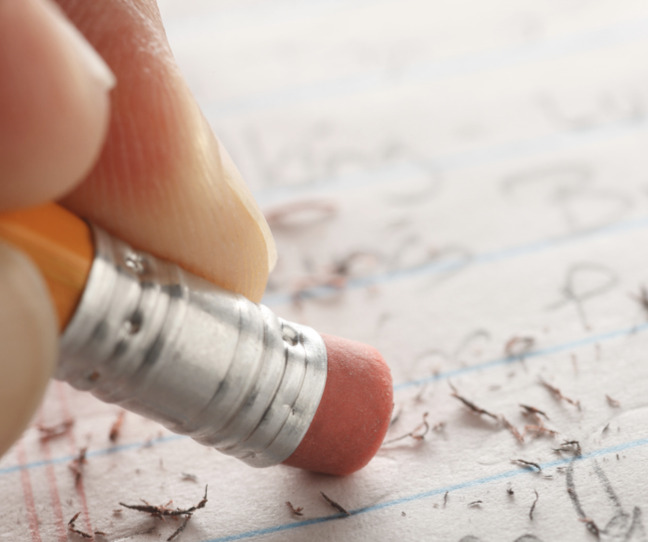 fingers erasing handwritten work with a pencil eraser