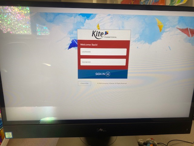 A computer monitor displaying the Kite Portal is shown. It shows a red log-in box on a white background.