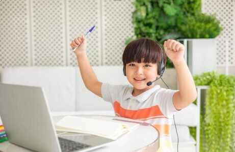 A young boy wearing headphones is sitting in front of a laptop computer.