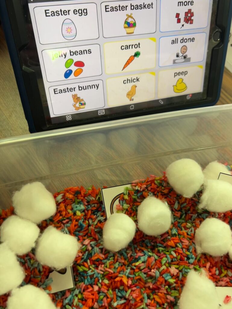 AAC on an iPad with Easter words, rainbow rice sensory bin with cotton balls and vocab cards