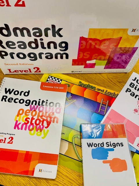 The box of the Edmark level 2 kit is shown, along with some of the components, such as a word recognition book, game board, and word signs CD.