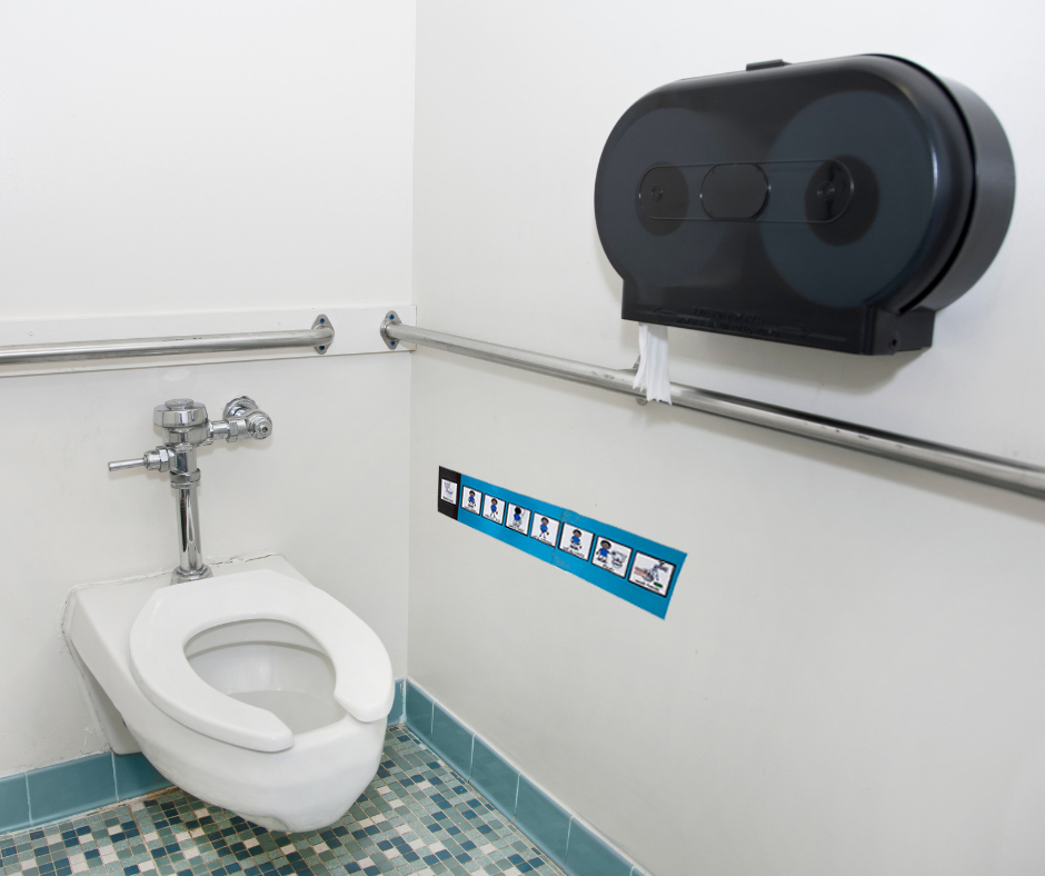 visuals for personal hygiene instruction are posted near a toilet in a school restroom