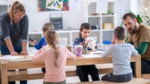 Featured image for "How to Support Paraprofessionals at the Start of the School Year." Image features two adults working with a small group of 4 students.
