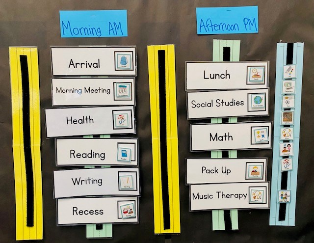 A black bulletin board with a daily classroom schedule shown. The schedule is divided into two parts, with he labels "morning AM" and "afternoon pm."