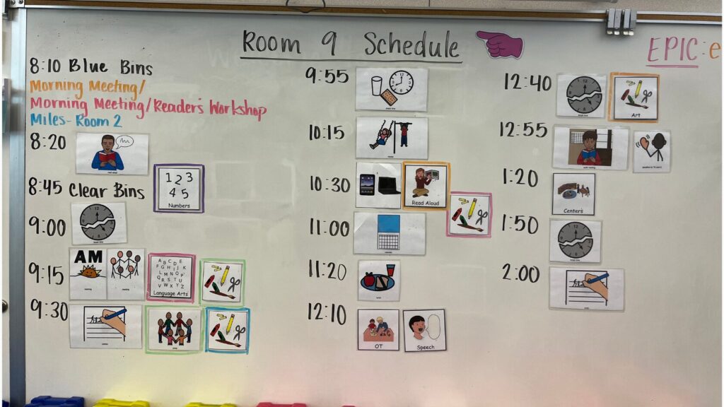 Image of a white board with the title "Room 9 Schedule." Image includes a lot of visuals depicting a classroom schedule.