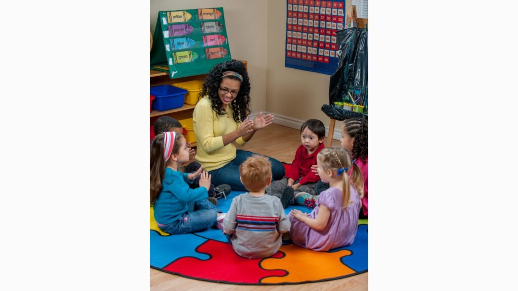 Image of an adult leading five students in circle time