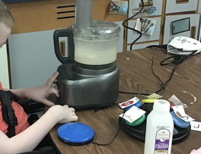 student operating a food processor with a blue switch
