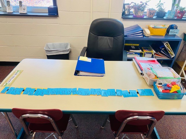 A table in a classroom with binders and work materials