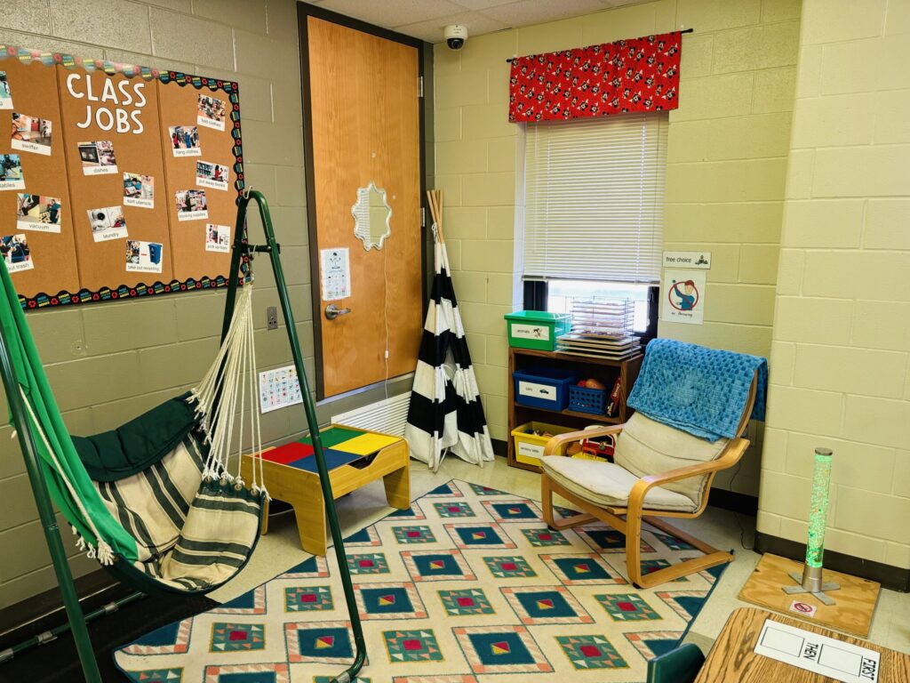 student free choice area with a swing, lego tabled, folded tent, shelf of toys, and a comfortable chair